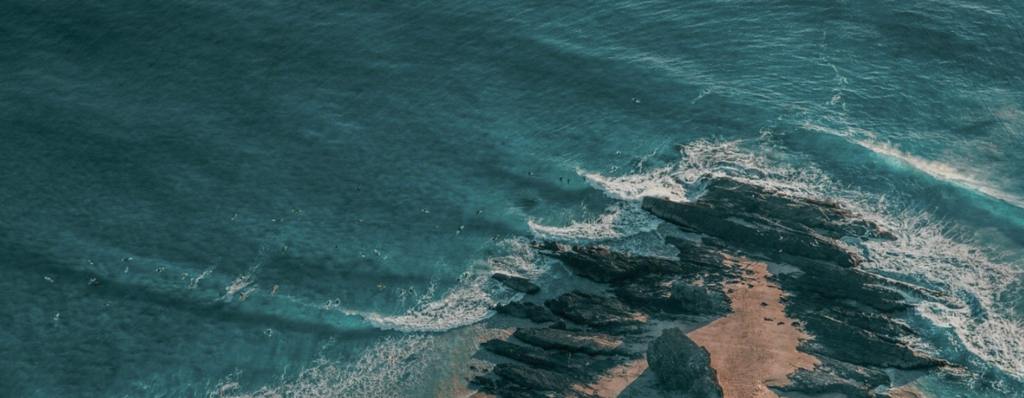 Aerial view of ocean waves meeting a sandy beach with rocks